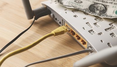 A selective focus shot of an internet modem with a dollar bill on top of it